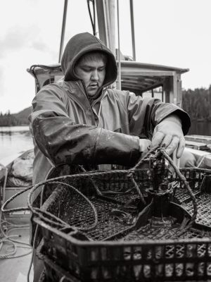 a person in a raincoat working on a fishing boat harvesting shellfish.